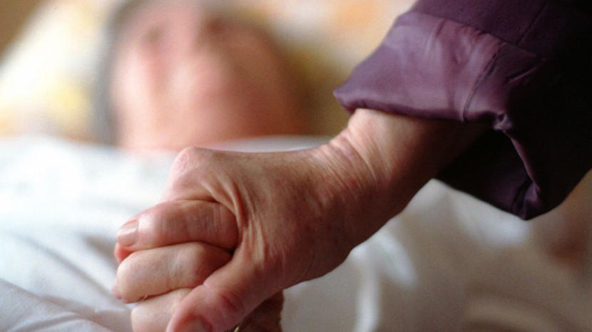 Eine Seelsorgerin hält die Hand einer Patientin.