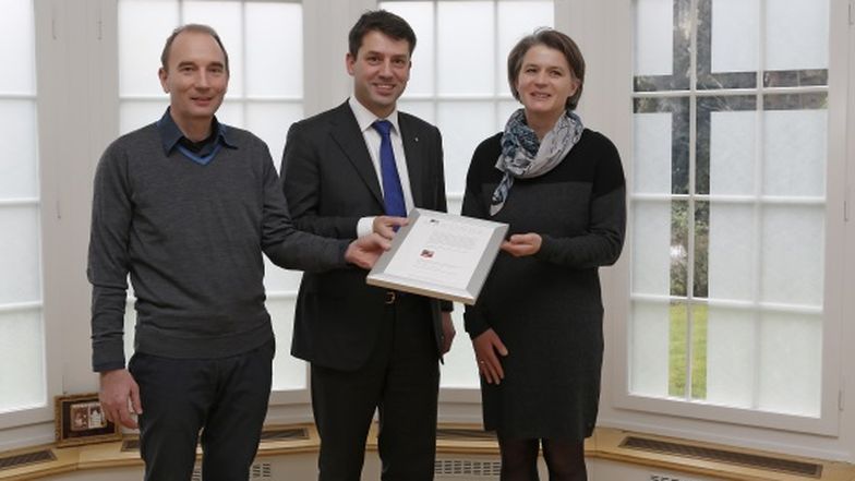 Daniel Huber (links), Geschäftsführer der Fachstelle UND, überreicht das Prädikat «Famille UND Beruf» an Gottfried Locher, Ratspräsident des Kirchenbundes, und Hella Hoppe, Leiterin Koordination Bundesbehörden und Genderbeauftragte des Kirchenbundes.