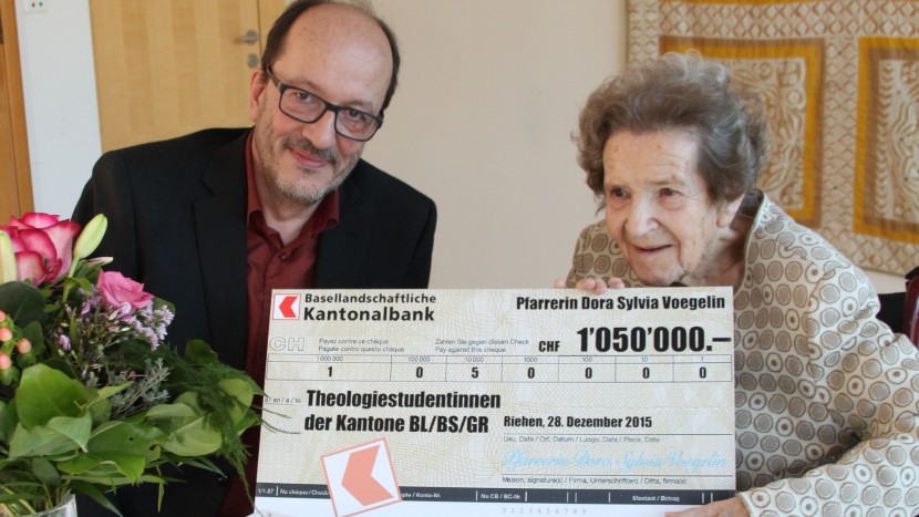 Pfarrerin Dora Sylvia Voegelin übergibt den Check für den Dora Sylvia Voegelin-Fonds an Pfarrer Martin Stingelin, Kirchenratspräsident der reformierten Kirche Baselland.