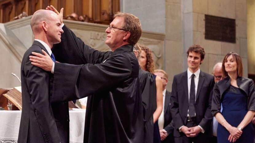 Ordinationsfeier im Zürcher Grossmünster: Kirchenratspräsident Michel Müller setzt einen neuen Pfarrer in sein Amt ein (August 2015).