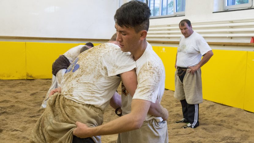 Rohoullah aus Afghanistan beim Schwingen. Im Hintergrund beobachtet Trainer und Schwingerkönig Ernst Schläpfer den Wettkampf.