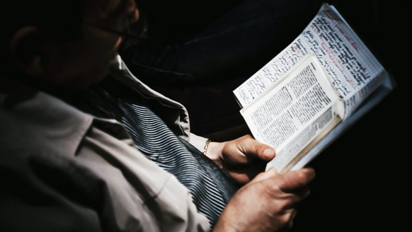 Mann hält Buch und Notizen in den Händen.